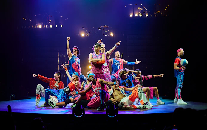 Performers in colorful costumes on stage during Mad Apple show.