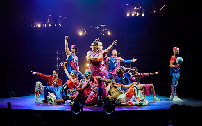 Performers in colorful costumes on stage during Mad Apple show.