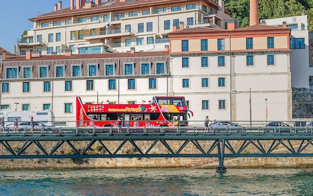 Hop on hop off bus crossing a bridge over the river in Porto, Portugal.