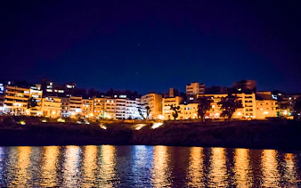 Athens Riviera cityscape at night with reflections on the Aegean Sea.