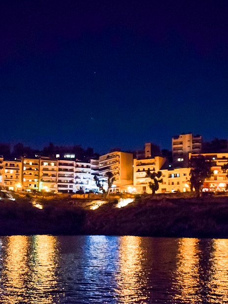 Athens Riviera cityscape at night with reflections on the Aegean Sea.