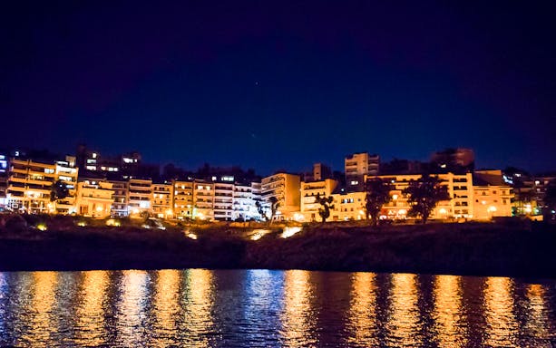 Athens Riviera cityscape at night with reflections on the Aegean Sea.