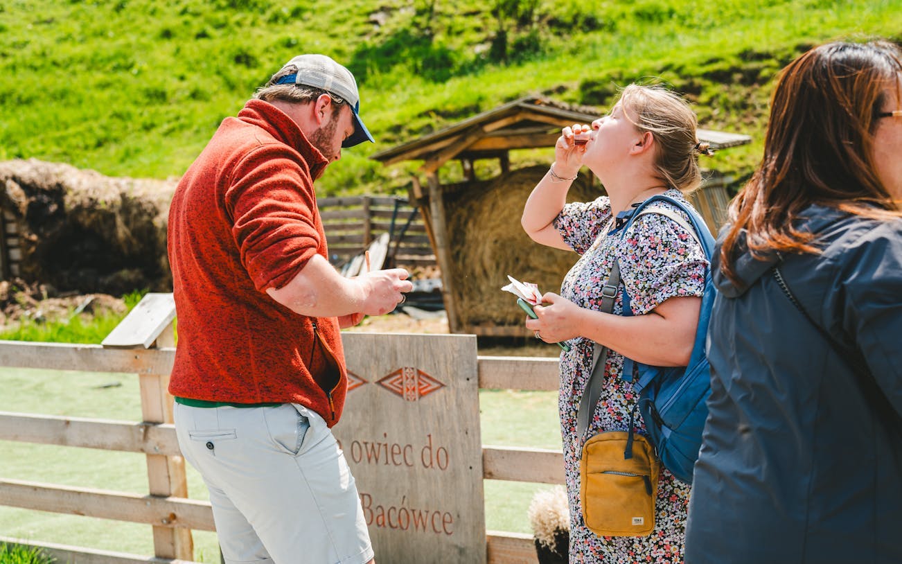 Tourists tasting cheese and vodka in Zakopane countryside during Krakow day trip.