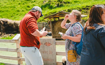 Tourists tasting cheese and vodka in Zakopane countryside during Krakow day trip.