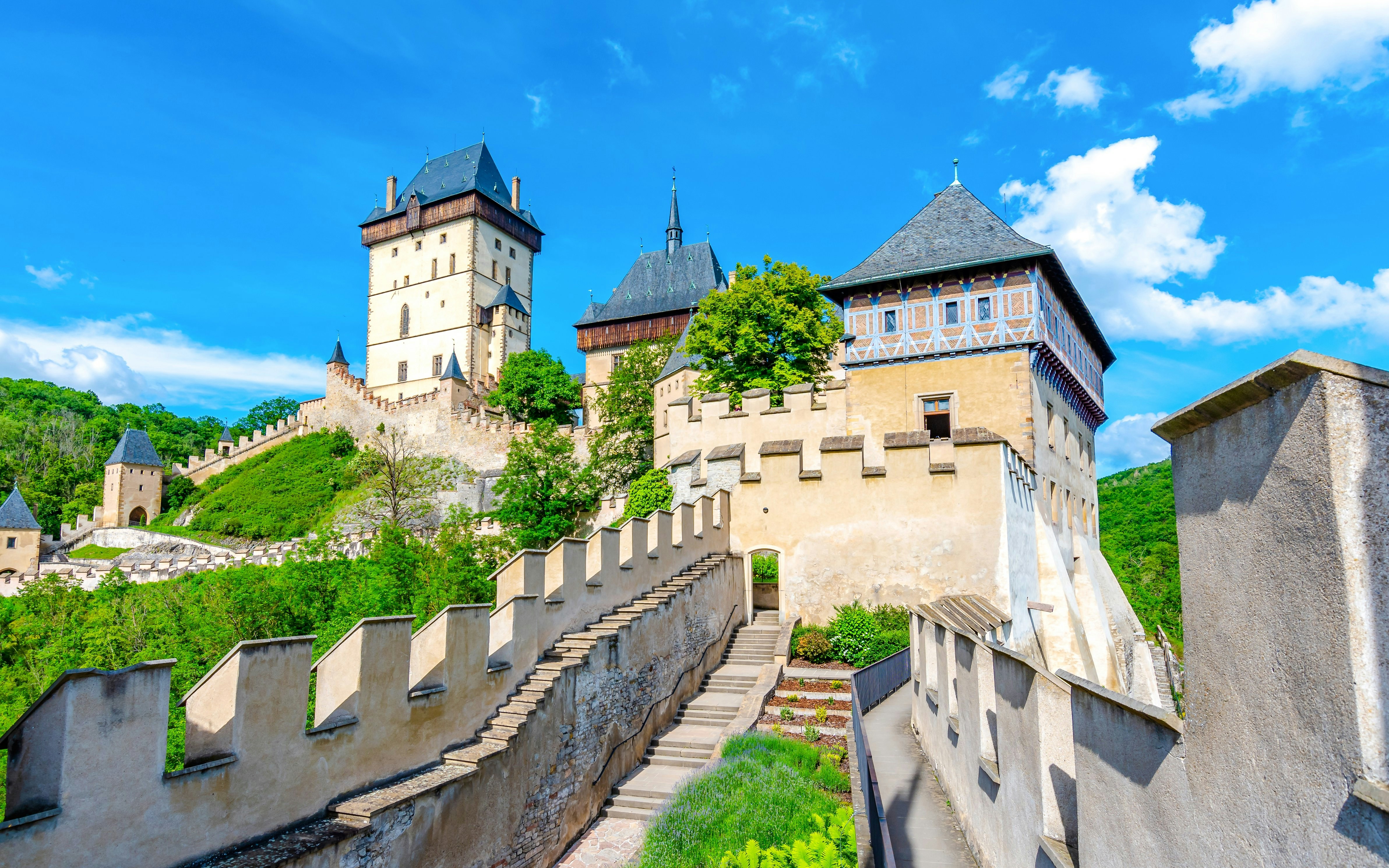 Karlstejn Castle with stone walls and towers surrounded by greenery, Czech Republic.