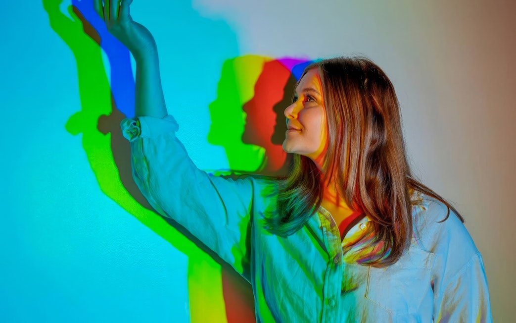 Person interacting with colorful light shadows at Museum of Illusions Dubai.
