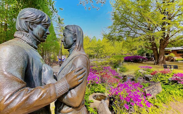 Statue of a couple surrounded by colorful flowers and trees on Nami Island, South Korea.