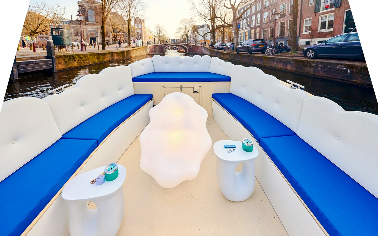 Amsterdam canal with tourists on a cloud boat cruise passing historic buildings.
