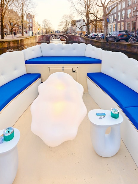 Cloud Boat Cruise seating on Amsterdam canal with bridge view.