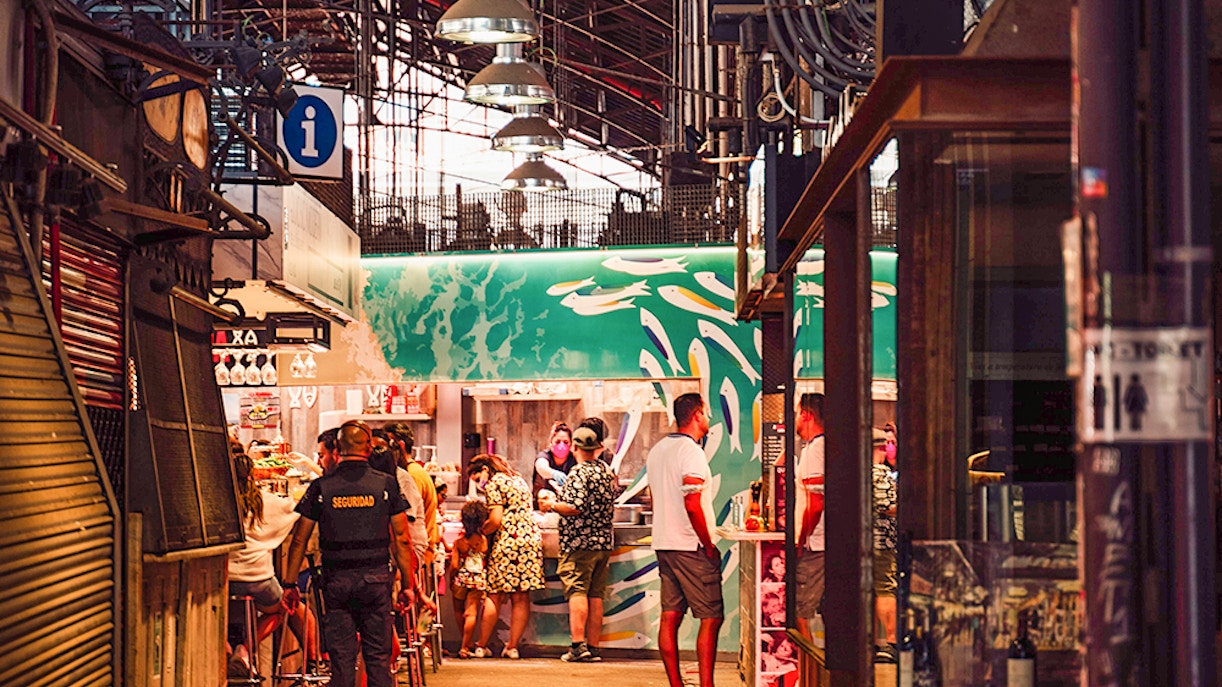 Visitors exploring food stalls at Mercado de La Boqueria, Barcelona.