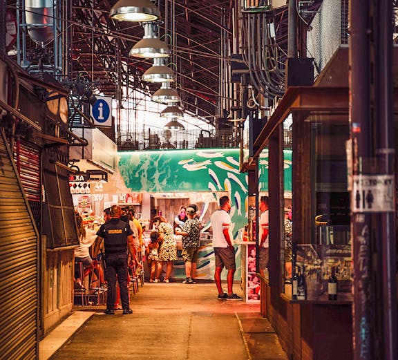 Visitors exploring food stalls at Mercado de La Boqueria, Barcelona.