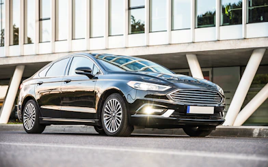 Sedan car parked outside modern building for private airport transfer.