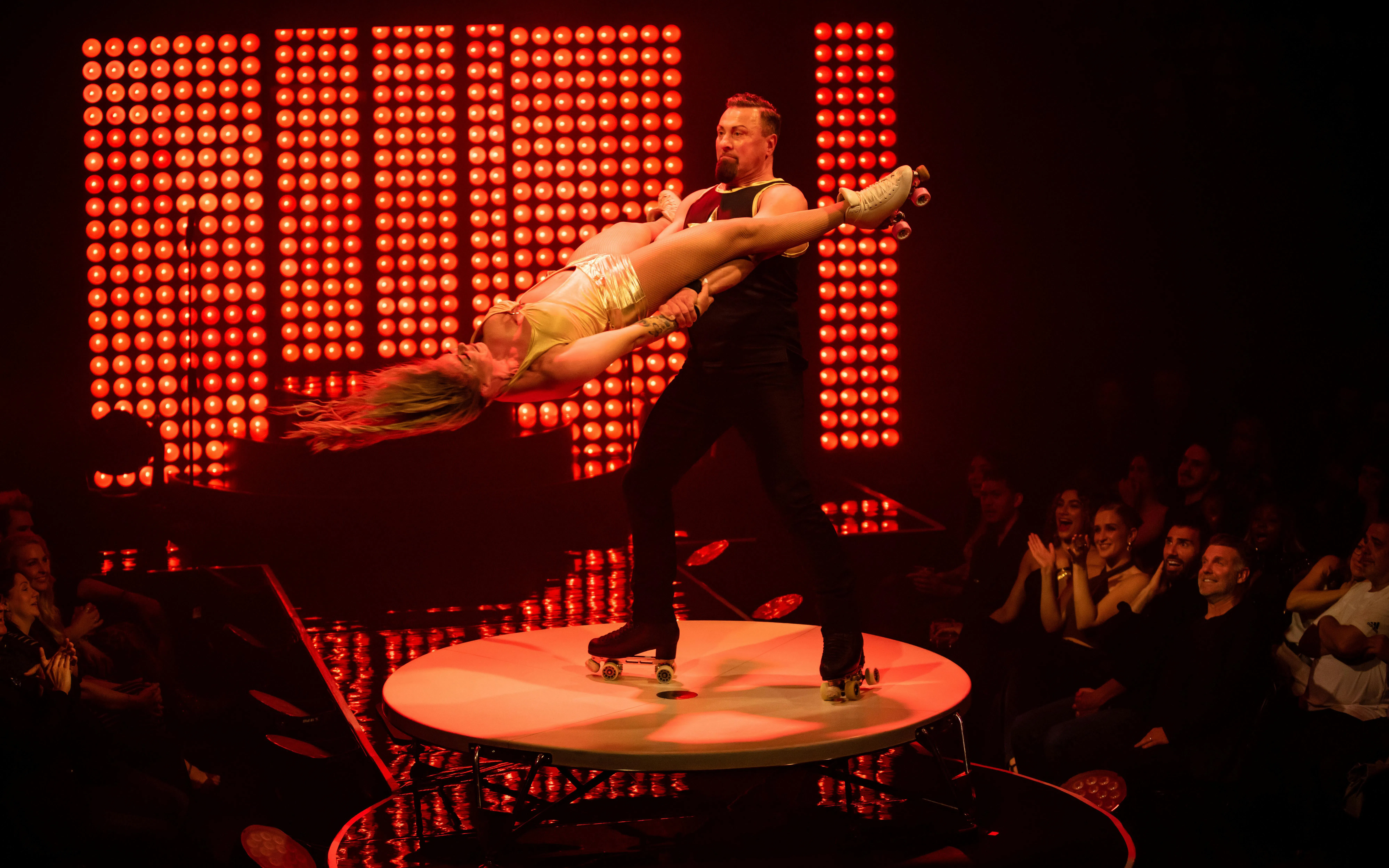 Roller skating duo performing acrobatic lift during Velvet Inferno show in Sydney.