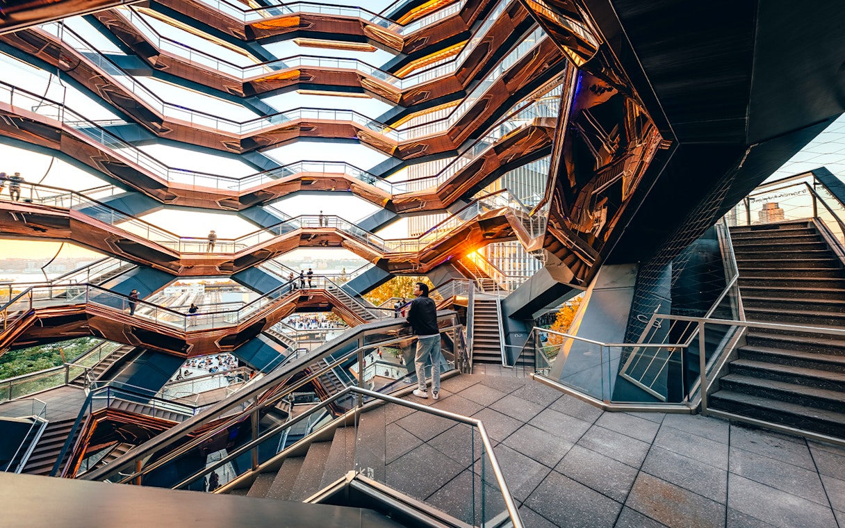 Vessel structure with visitors on staircases at sunset, New York City.
