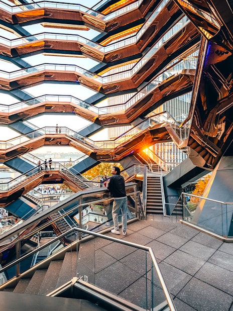 Vessel structure with visitors on staircases at sunset, New York City.