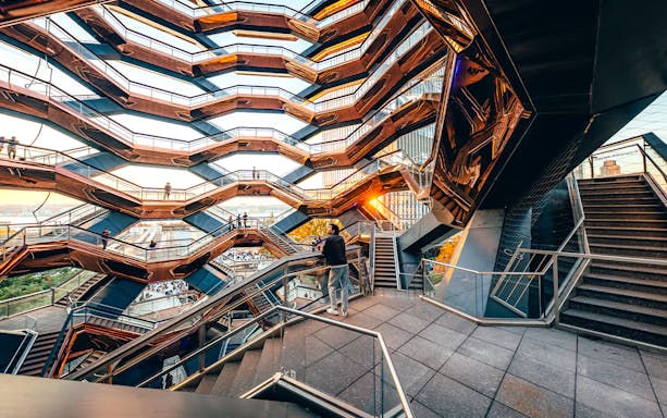 Vessel structure with visitors on staircases at sunset, New York City.