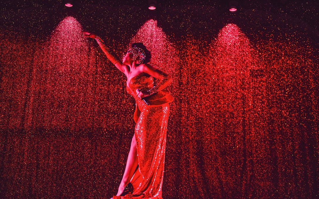Performer in a sparkling red dress on stage at Paradis Latin festive show.