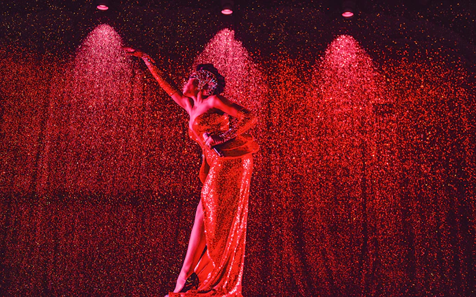 Performer in a sparkling red dress on stage at Paradis Latin festive show.