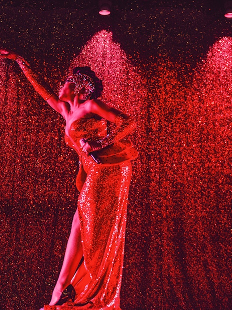 Performer in a sparkling red dress on stage at Paradis Latin festive show.