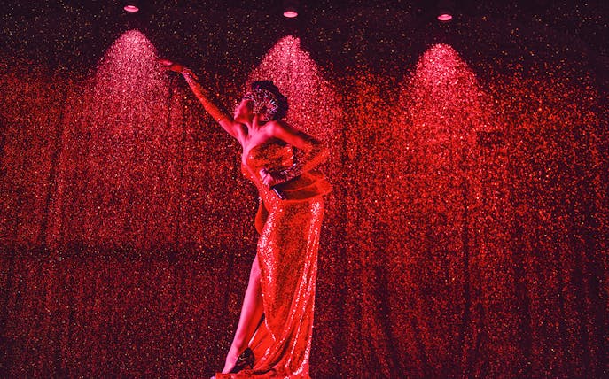Performer in a sparkling red dress on stage at Paradis Latin festive show.