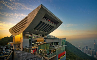 Hong Kong Peak Tower at sunset with city skyline and harbor view.