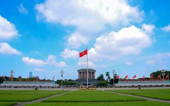 Ho Chi Minh Mausoleum with Vietnamese flag in Hanoi, part of city tour.