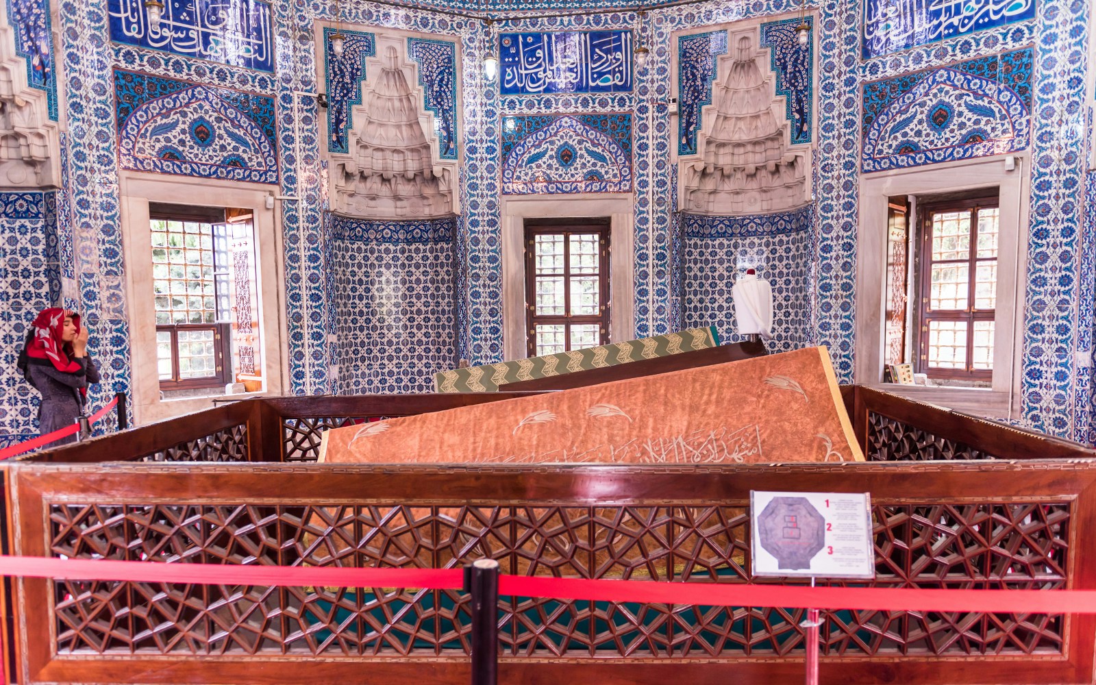 Tomb inside Suleymaniye Mosque with intricate blue tilework and a visitor.
