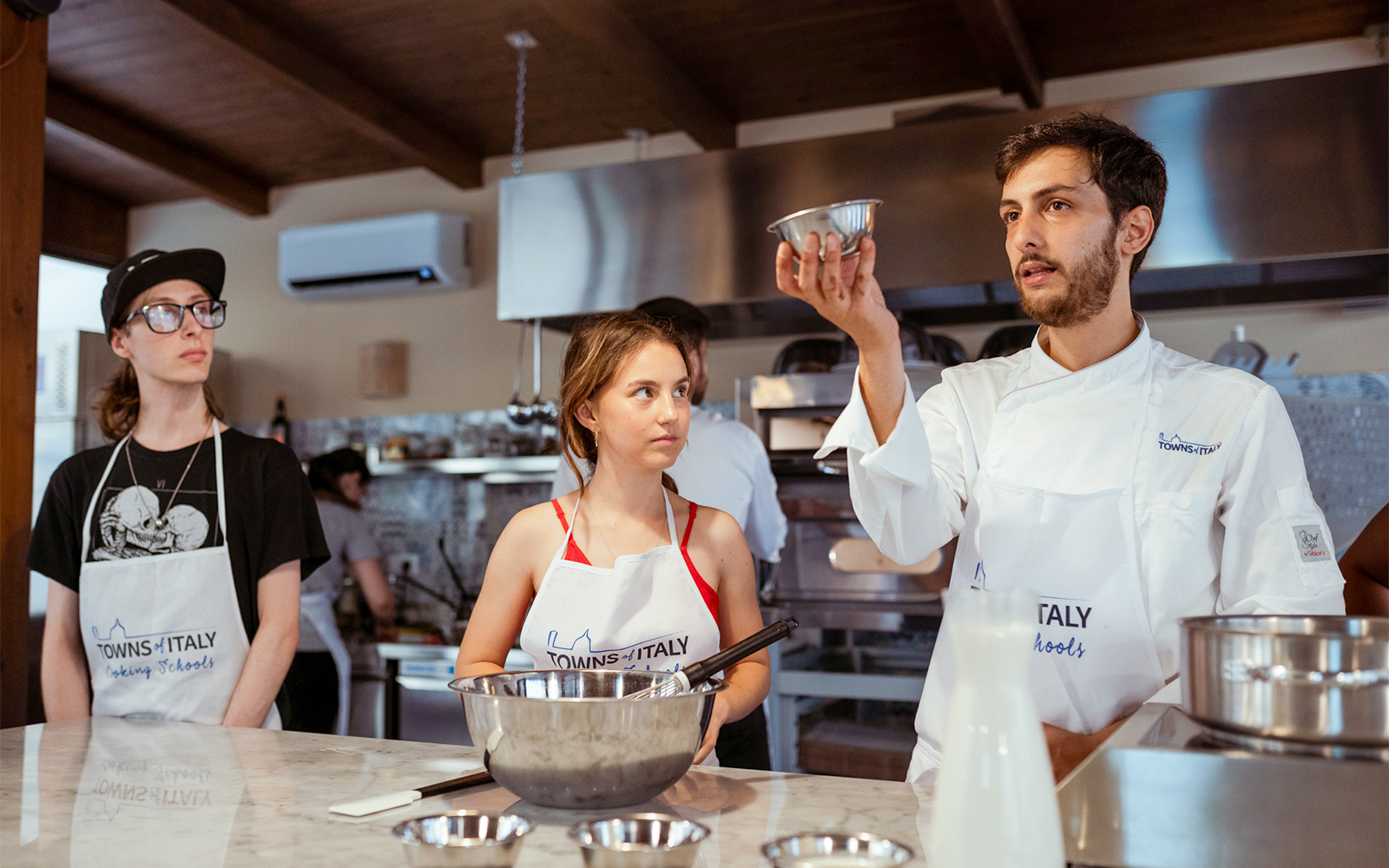 Cooking class participants learning from a chef in Palermo kitchen.