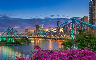 Brisbane Story Bridge at twilight with city skyline in the background.