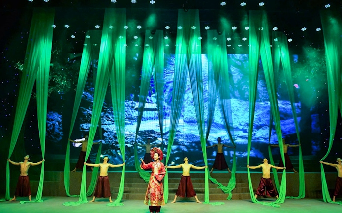 Performers on stage with green drapes at Charming Danang Show in Da Nang.