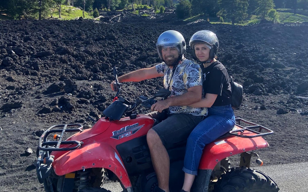 Couple on a quad bike exploring volcanic terrain during Alcantara Gorges tour.