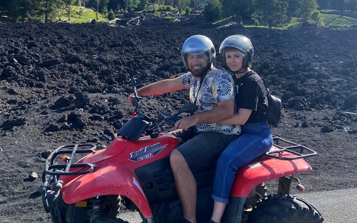 Couple on a quad bike exploring volcanic terrain during Alcantara Gorges tour.