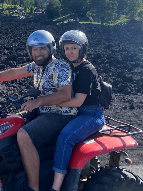 Couple on a quad bike exploring volcanic terrain during Alcantara Gorges tour.