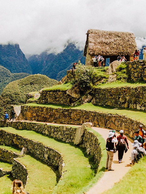 Tourists exploring terraces and stone structures at Machu Picchu, Peru.