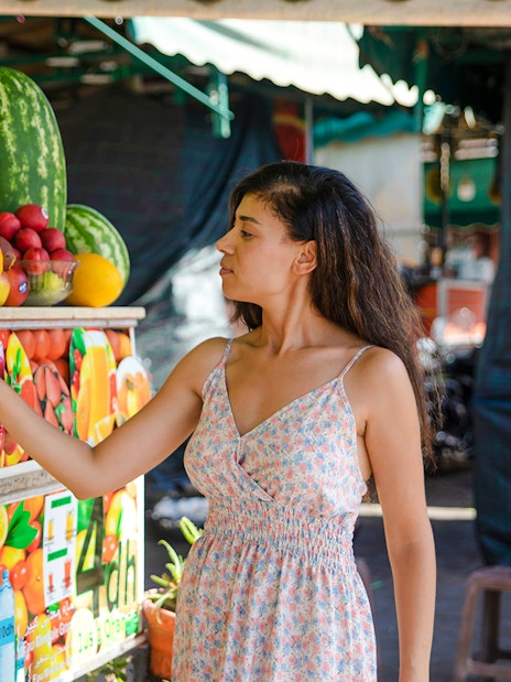 Woman selecting fruit at a market stall in Jema el Fna, Marrakesh.