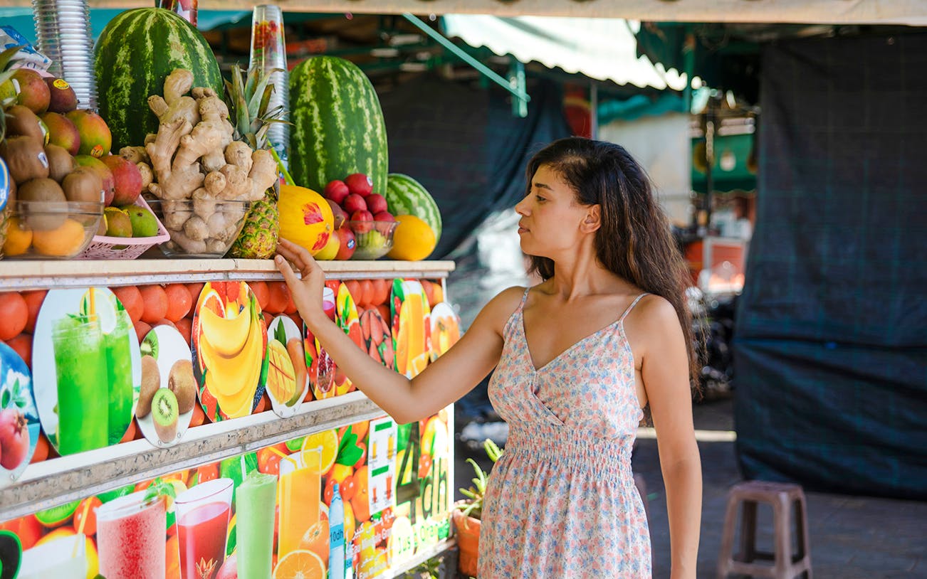 Woman selecting fruit at a market stall in Jema el Fna, Marrakesh.