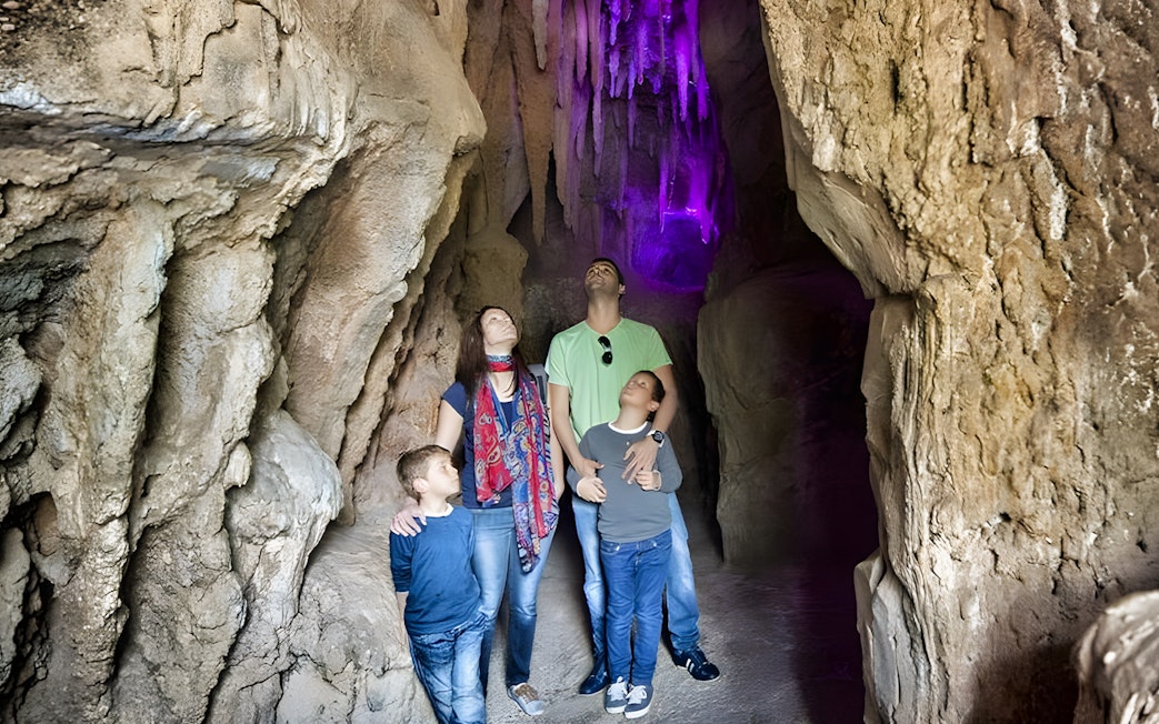 Family exploring illuminated cave at Jungle Park Tenerife's batcave experience.