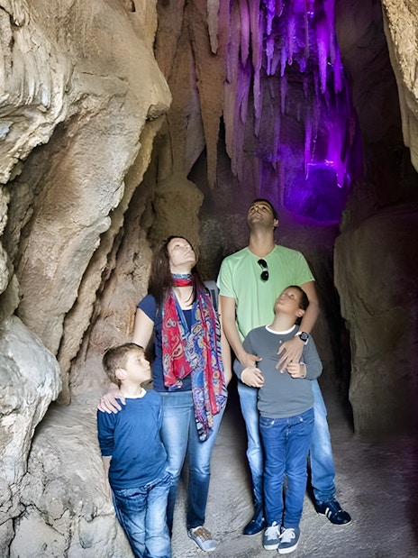 Family exploring illuminated cave at Jungle Park Tenerife's batcave experience.