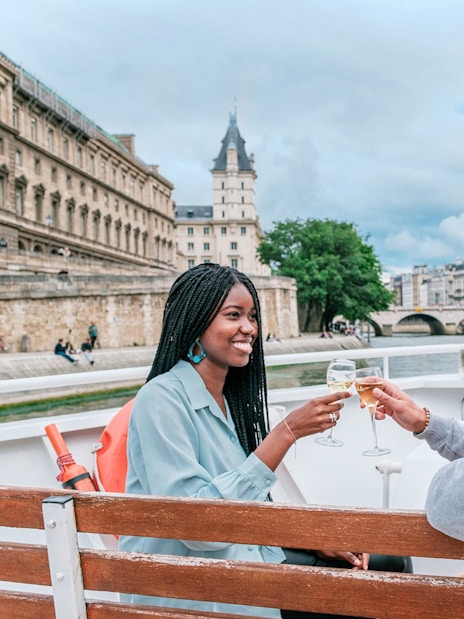 Couple enjoying a Seine River cruise in Paris with historic buildings in the background.