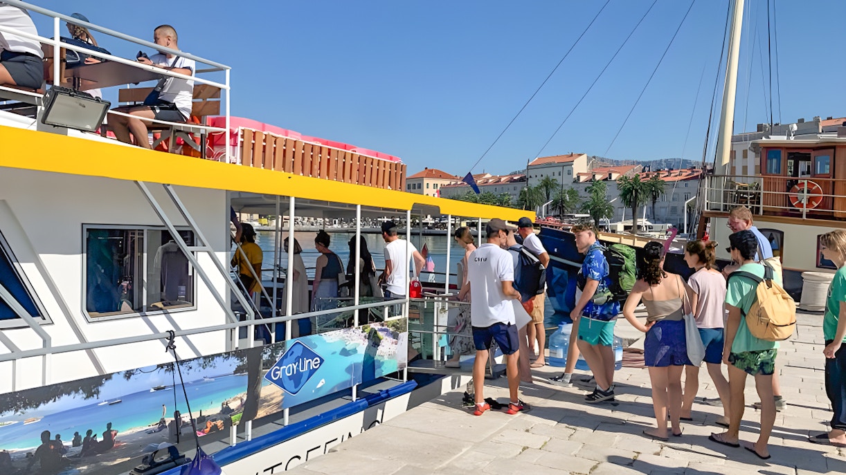 Tourists boarding a boat for Split, Hvar, and three islands cruise with lunch and drinks.