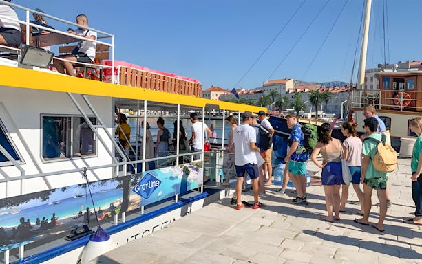 Tourists boarding a boat for Split, Hvar, and three islands cruise with lunch and drinks.