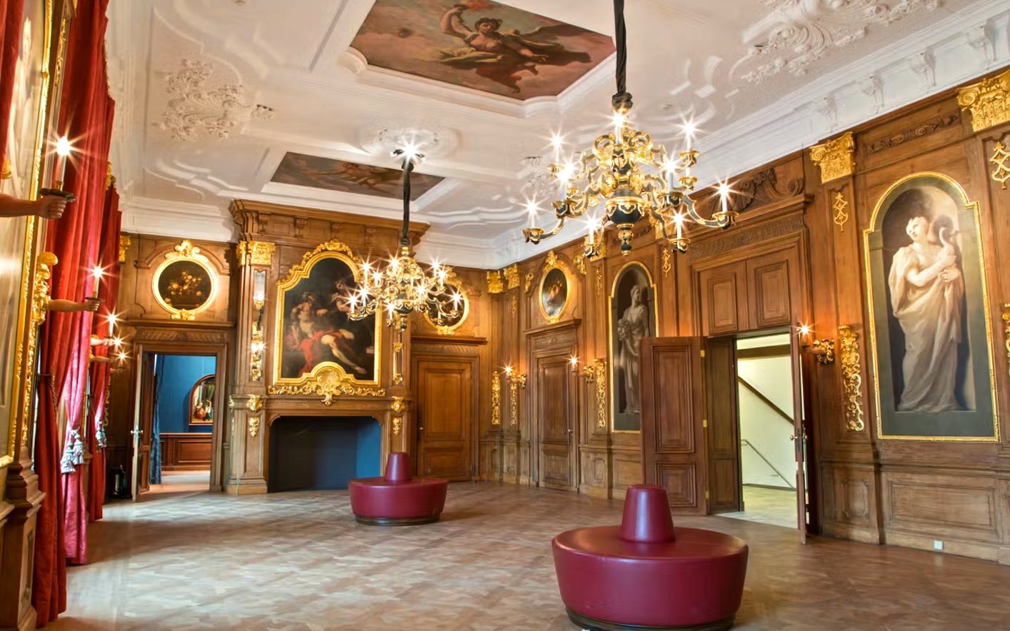 Mauritshuis museum interior with ornate chandeliers and classical paintings.