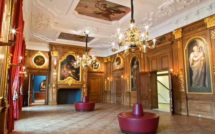 Mauritshuis museum interior with ornate chandeliers and classical paintings.