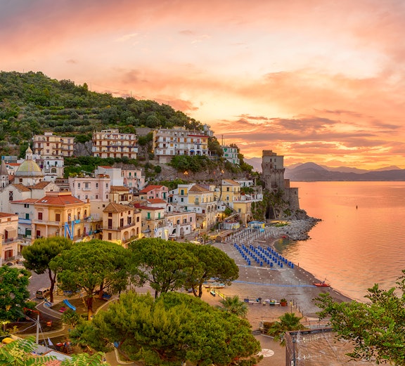 Amalfi Coast village at sunset with colorful buildings and beach, Italy.
