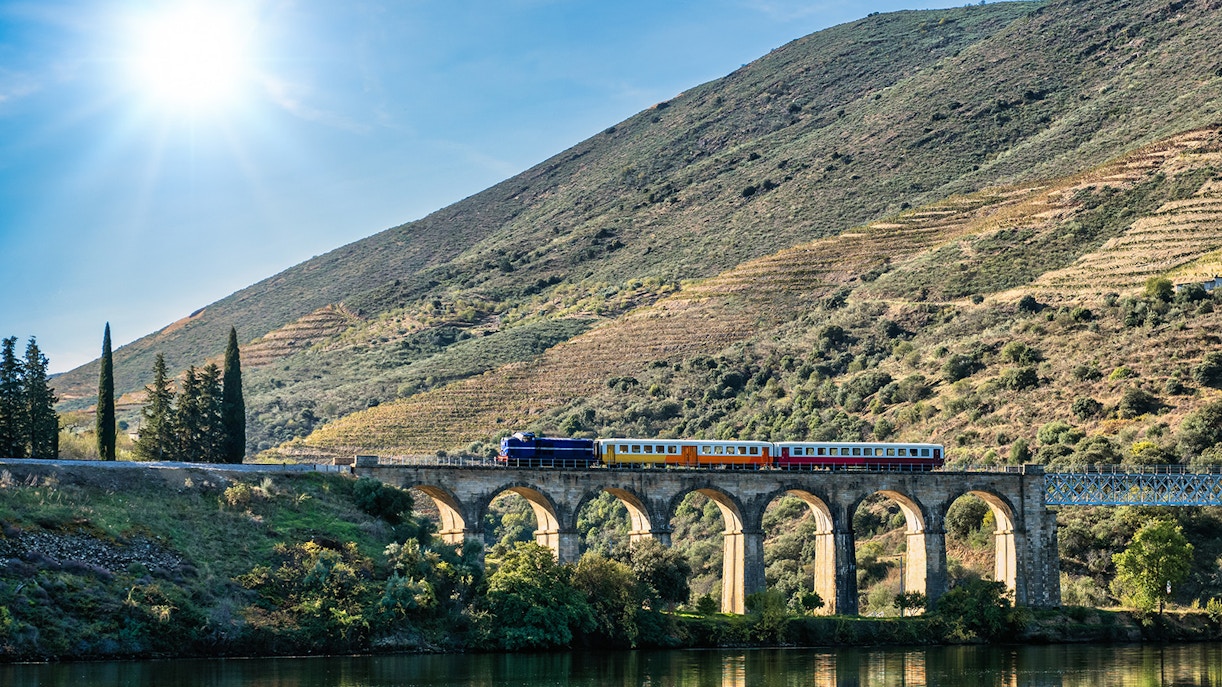 Train crossing a viaduct on the Duoro Railway line, Porto to Pochino, with hillside vineyards.