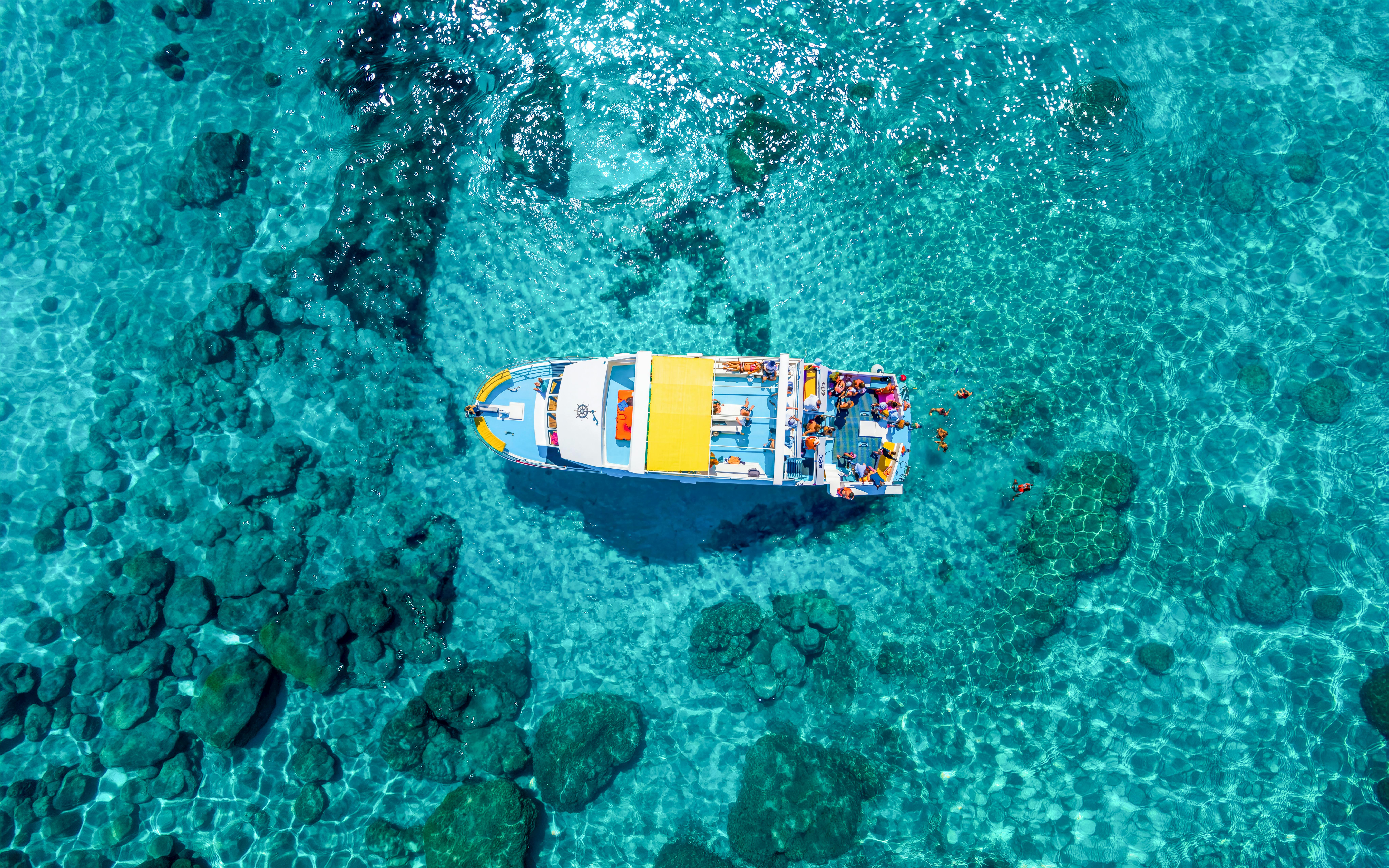 Aerial view of a boat cruising in the clear waters of the Blue Lagoon near Latchi, Cyprus.