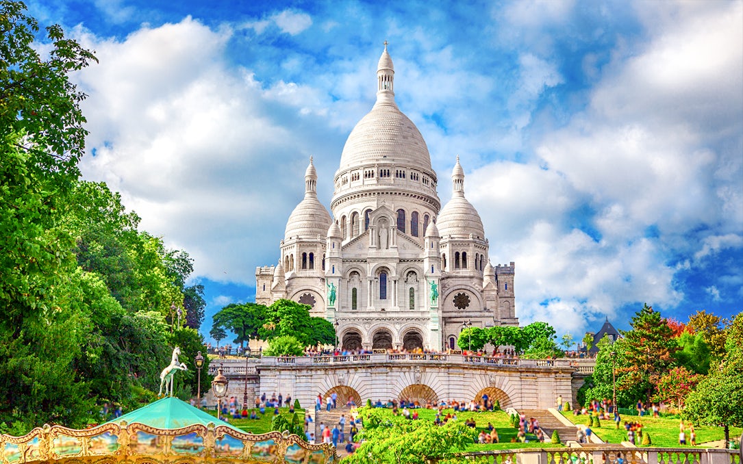 Sacre-Coeur Basilica in Montmartre, Paris, with tourists and greenery.
