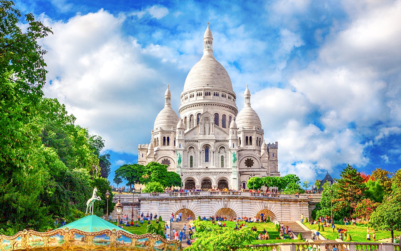 Sacre-Coeur Basilica in Montmartre, Paris, with tourists and greenery.