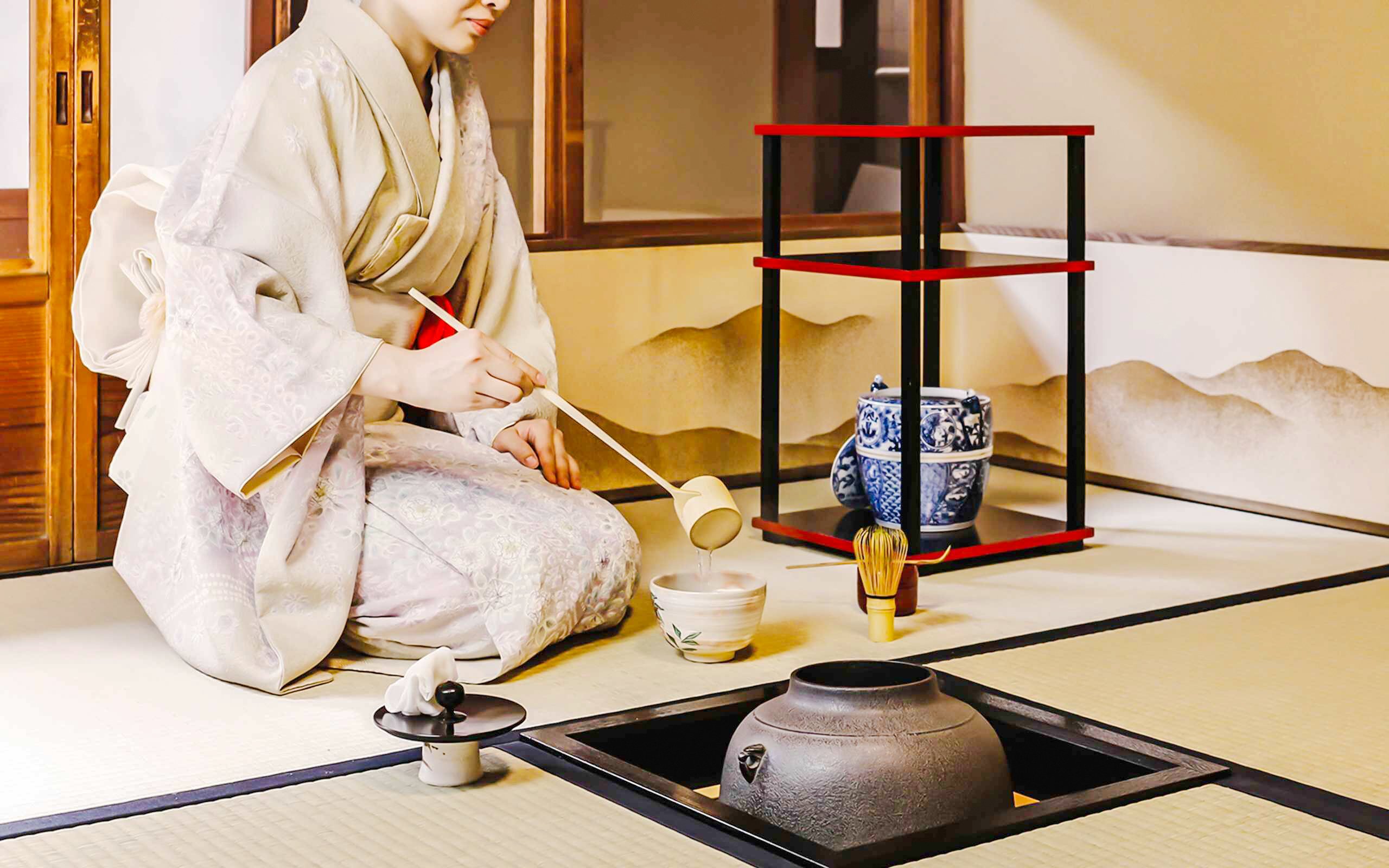 Person performing traditional Japanese tea ceremony with matcha tools.