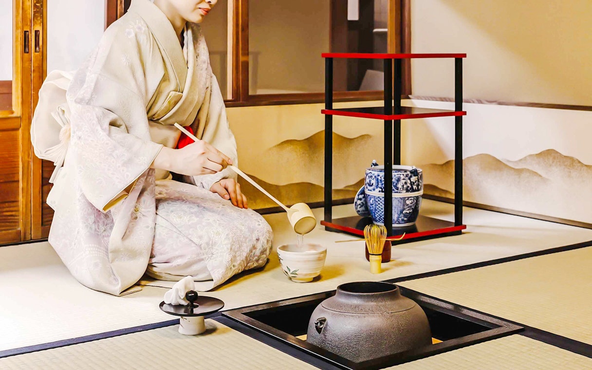 Person performing traditional Japanese tea ceremony with matcha tools.